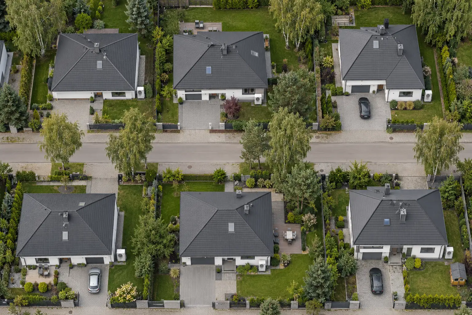 Aerial view of a quiet residential street with detached houses, gardens and trees